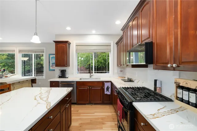 a large kitchen with stainless steel appliances granite countertop a sink a stove counter space and cabinets