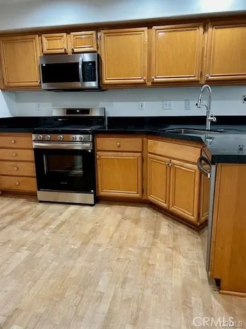 a kitchen with stainless steel appliances granite countertop a stove a sink and a microwave