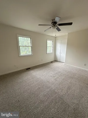 an empty room with windows and ceiling fan