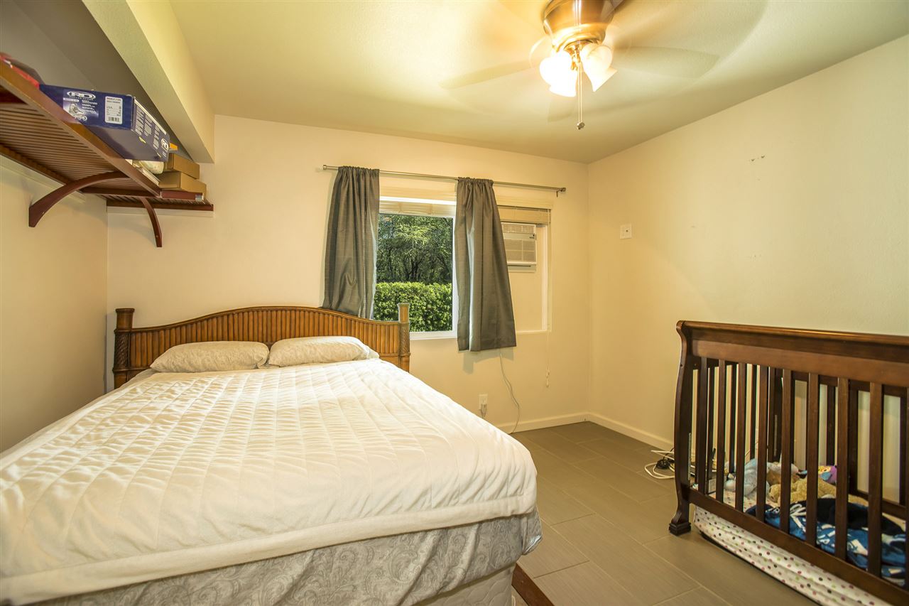 98 East Welakahao Road Kihei, HI 96753 - Photo 13 of 26 a bedroom with a bed and a chandelier