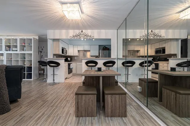 a view of a kitchen with kitchen island stainless steel appliances a stove a sink and a dining table
