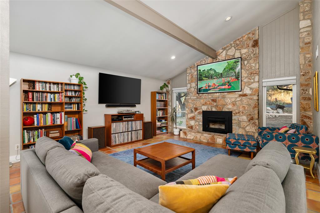2210 Red Fox Road Austin, TX 78734 - Photo 9 of 40 An inviting living area showcases a vaulted ceiling, exposed beam, and a robust stone fireplace for ultimate comfort.