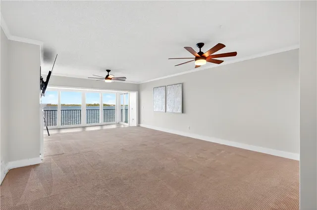an empty room with chandelier fan and windows