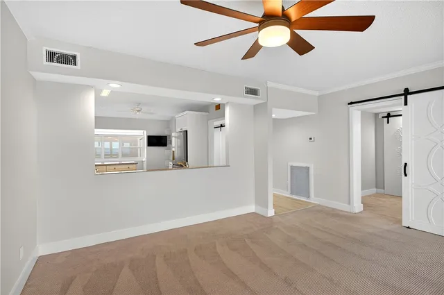 a view of an empty room with wooden floor and a ceiling fan