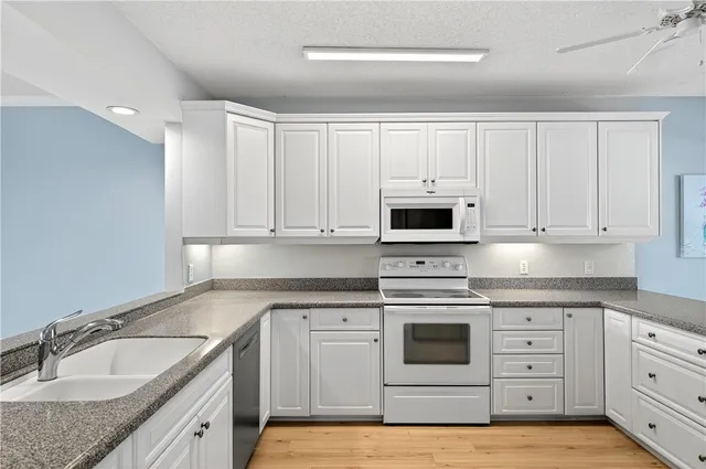 a kitchen with granite countertop white cabinets and white appliances
