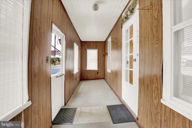 a view of an empty room with wooden floor and a bathroom