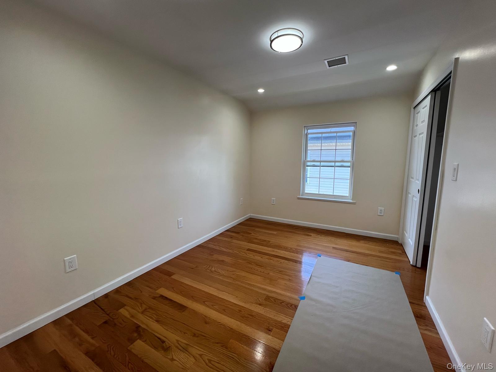 153-33 119th Road Queens, NY 11434 - Photo 6 of 9 an empty room with wooden floor and windows