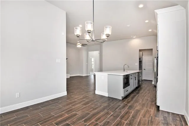 a view of a kitchen with kitchen island a sink wooden floor and a large window