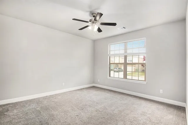 an empty room with a window and a fan