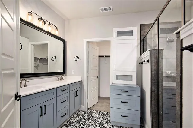 a bathroom with a double vanity sink a mirror a shower and a glass door