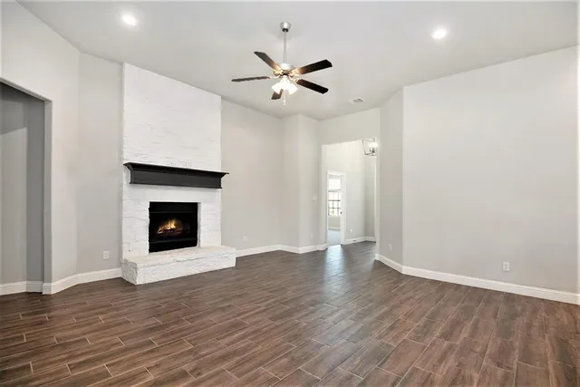 a view of an empty room with wooden floor a fireplace