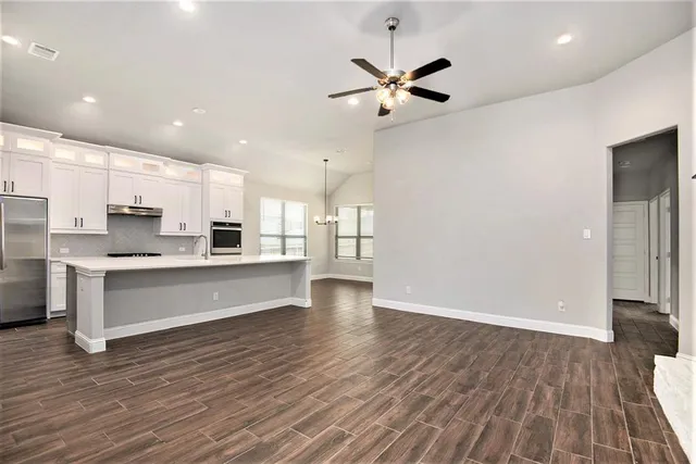 a large kitchen with stainless steel appliances a large counter top a sink and a refrigerator