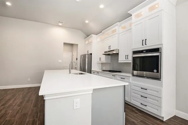 a kitchen with a sink a microwave and cabinets
