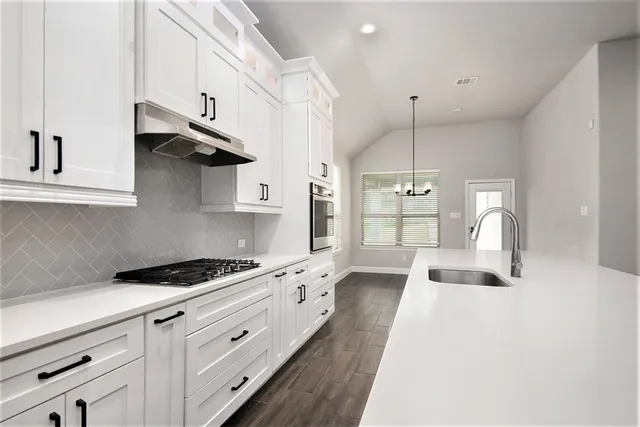 a kitchen with stainless steel appliances granite countertop a stove and a white cabinets