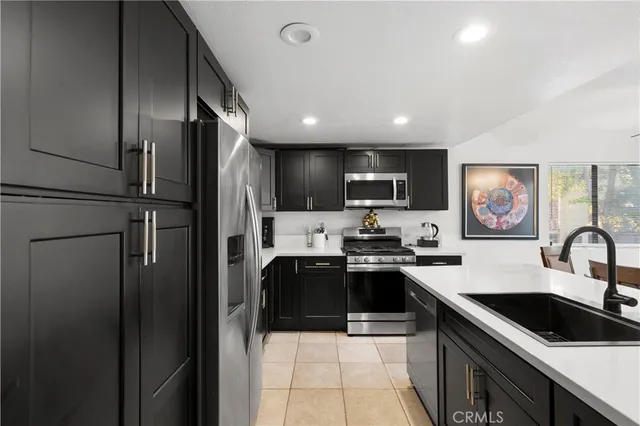 a kitchen with stainless steel appliances granite countertop a refrigerator a sink a stove top oven a granite counter space and cabinets