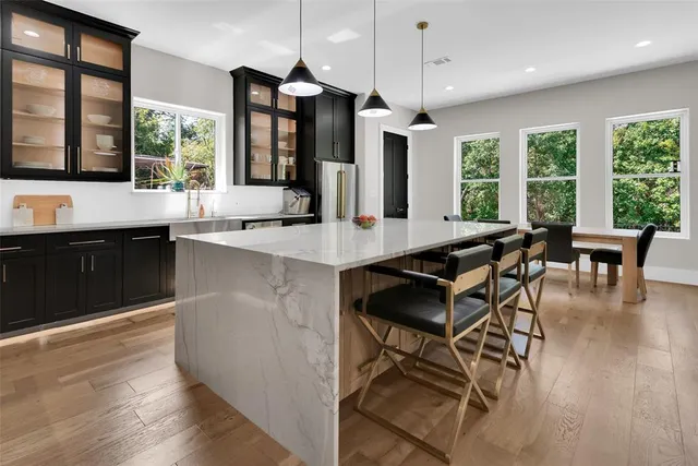 a kitchen with granite countertop a stove a sink a dining table and chairs