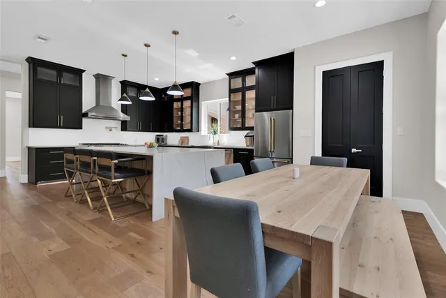 a kitchen with stainless steel appliances kitchen island granite countertop a table chairs sink and cabinets