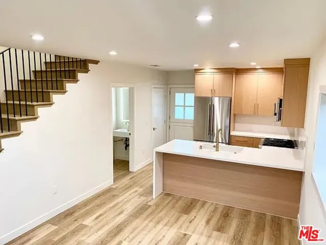 a large white kitchen with a sink and refrigerator