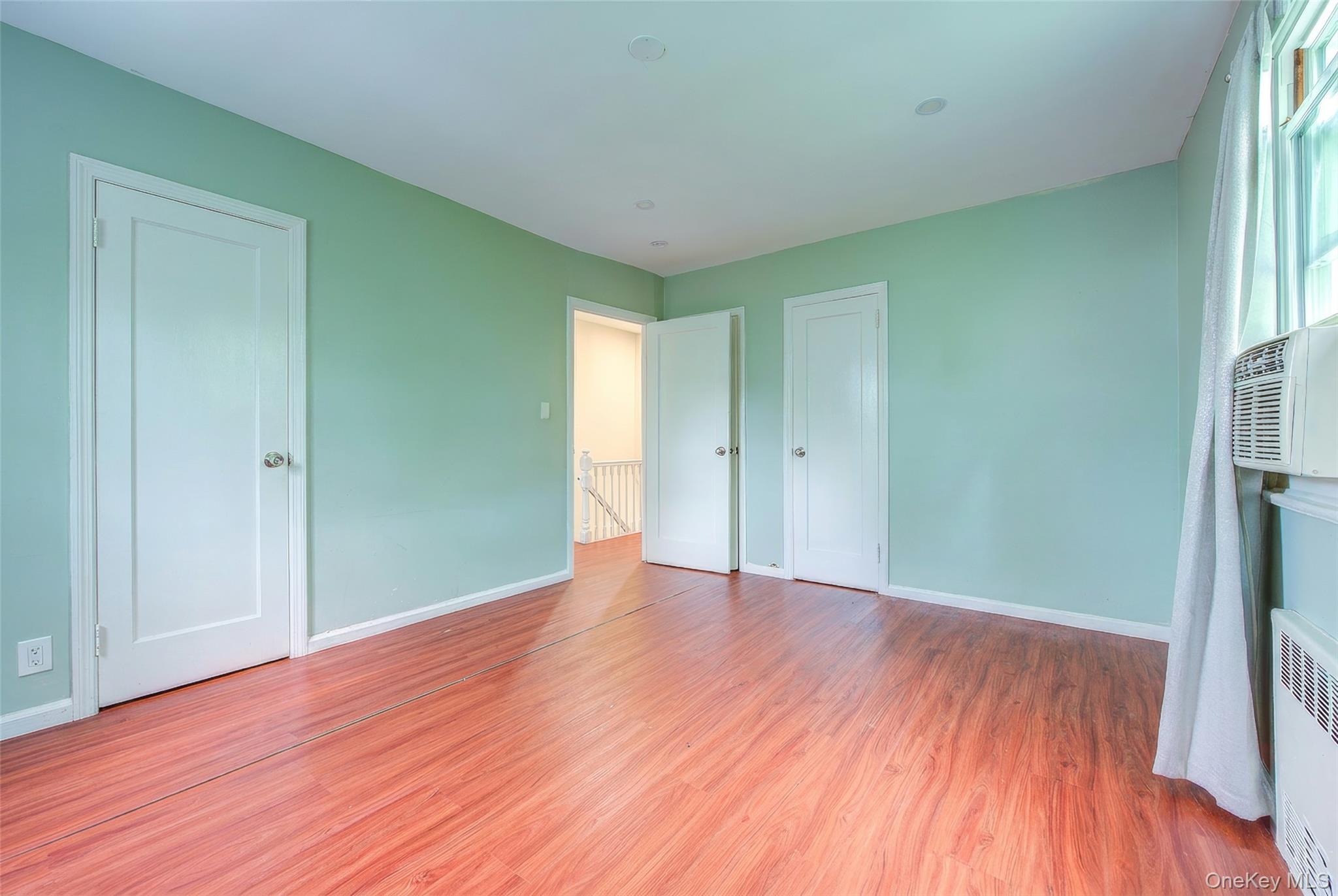 164-38 76th Road Queens, NY 11366 - Photo 17 of 44 a view of an empty room with wooden floor and a window
