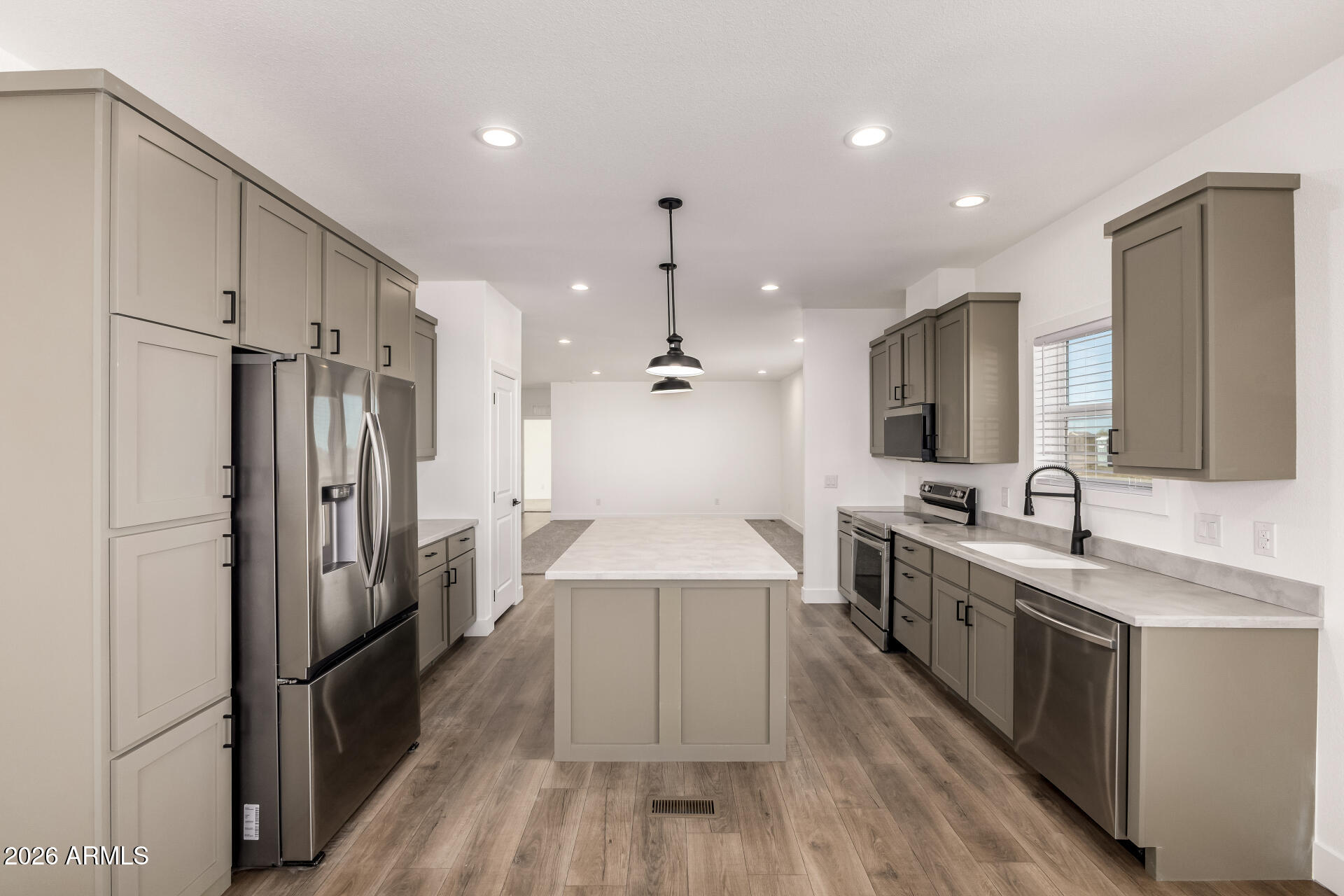 23059 West Rancho Laredo Drive Wittmann, AZ 85361 - Photo 6 of 29 a large kitchen with stainless steel appliances a refrigerator a sink dishwasher a oven and a dining table with wooden floor