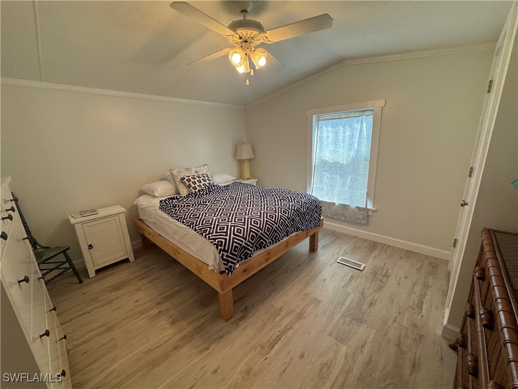3813 Dewberry Lane St. James City, FL 33956 - Photo 6 of 9 a bedroom with a bed and a chandelier