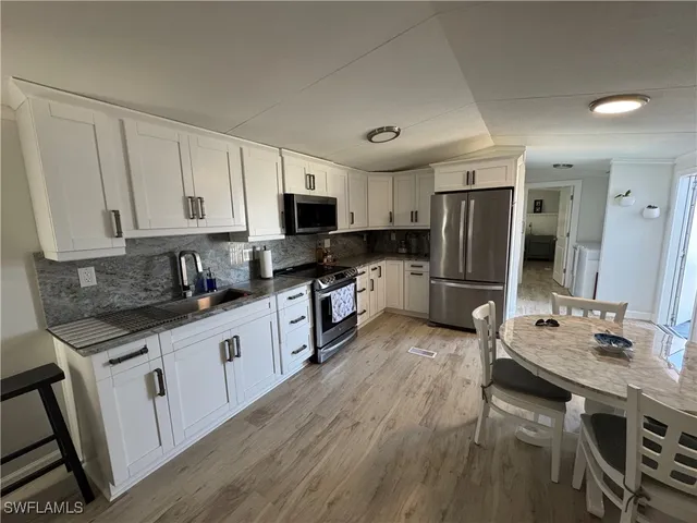 a large kitchen with cabinets wooden floor and stainless steel appliances
