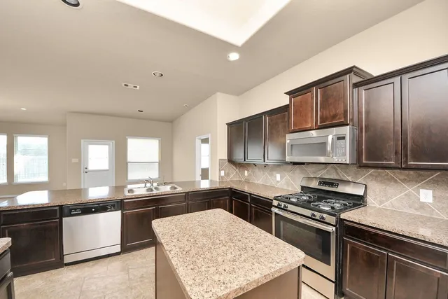 a kitchen with stainless steel appliances granite countertop a stove a sink and a microwave