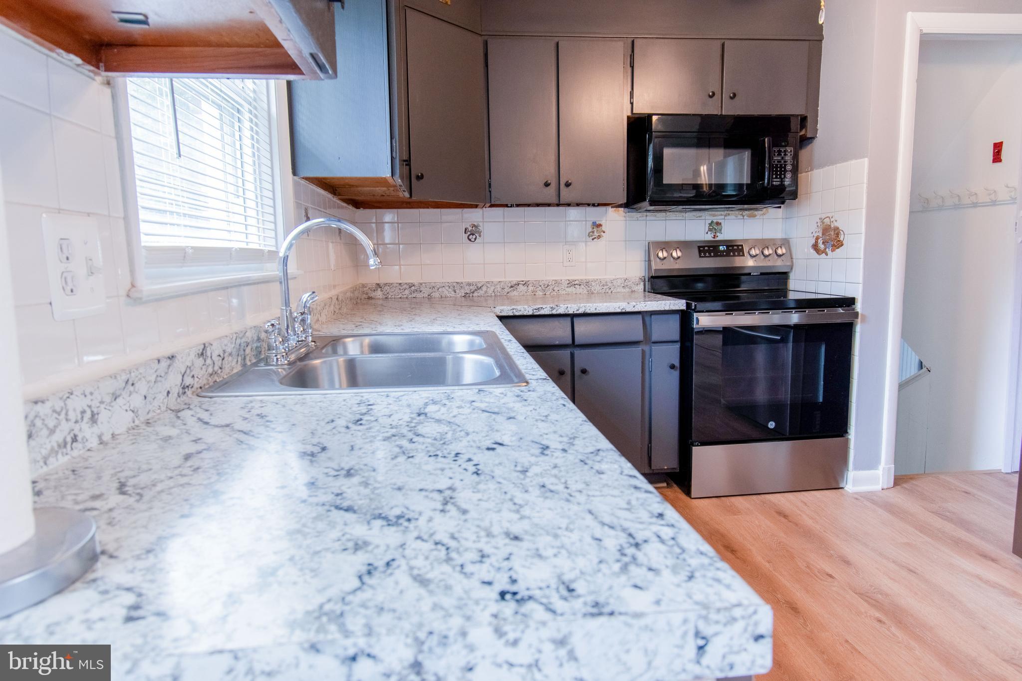 3911 Sunset Drive Hampstead, MD 21074 - Photo 12 of 38 a kitchen with stainless steel appliances granite countertop a sink stove microwave and refrigerator