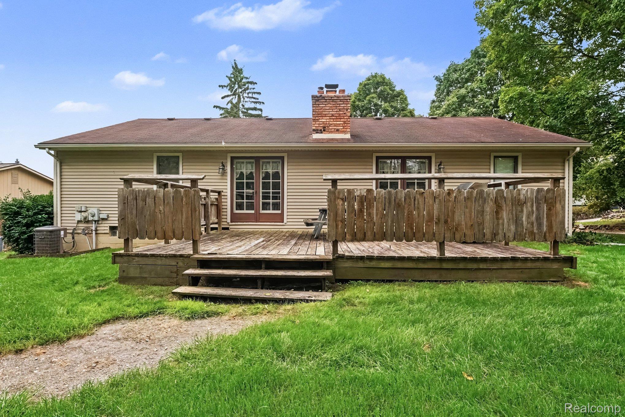 107 Michelle Drive Romeo, MI 48065 - Photo 30 of 30 Expansive wooden deck with railing, accessible via double doors and steps to the lawn