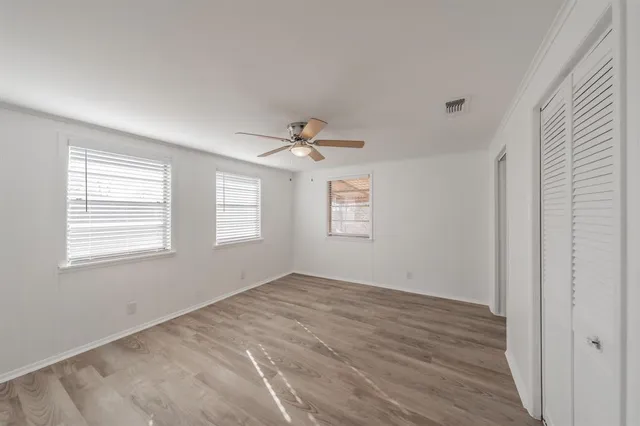 a view of empty room with wooden floor and fan