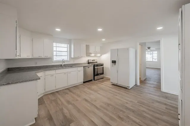 a kitchen with stainless steel appliances granite countertop a refrigerator sink and white cabinets