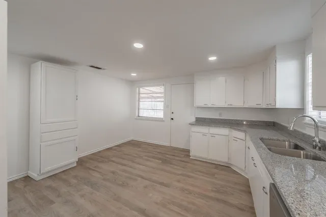 a kitchen with granite countertop white cabinets and sink