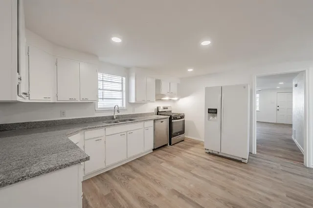 a large kitchen with stainless steel appliances granite countertop a sink and cabinets