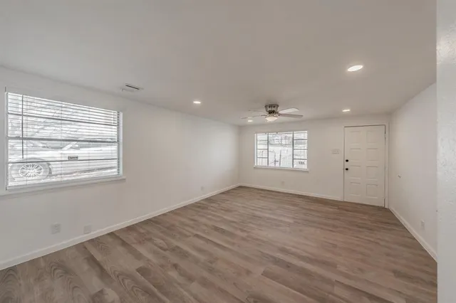 an empty room with wooden floor and windows