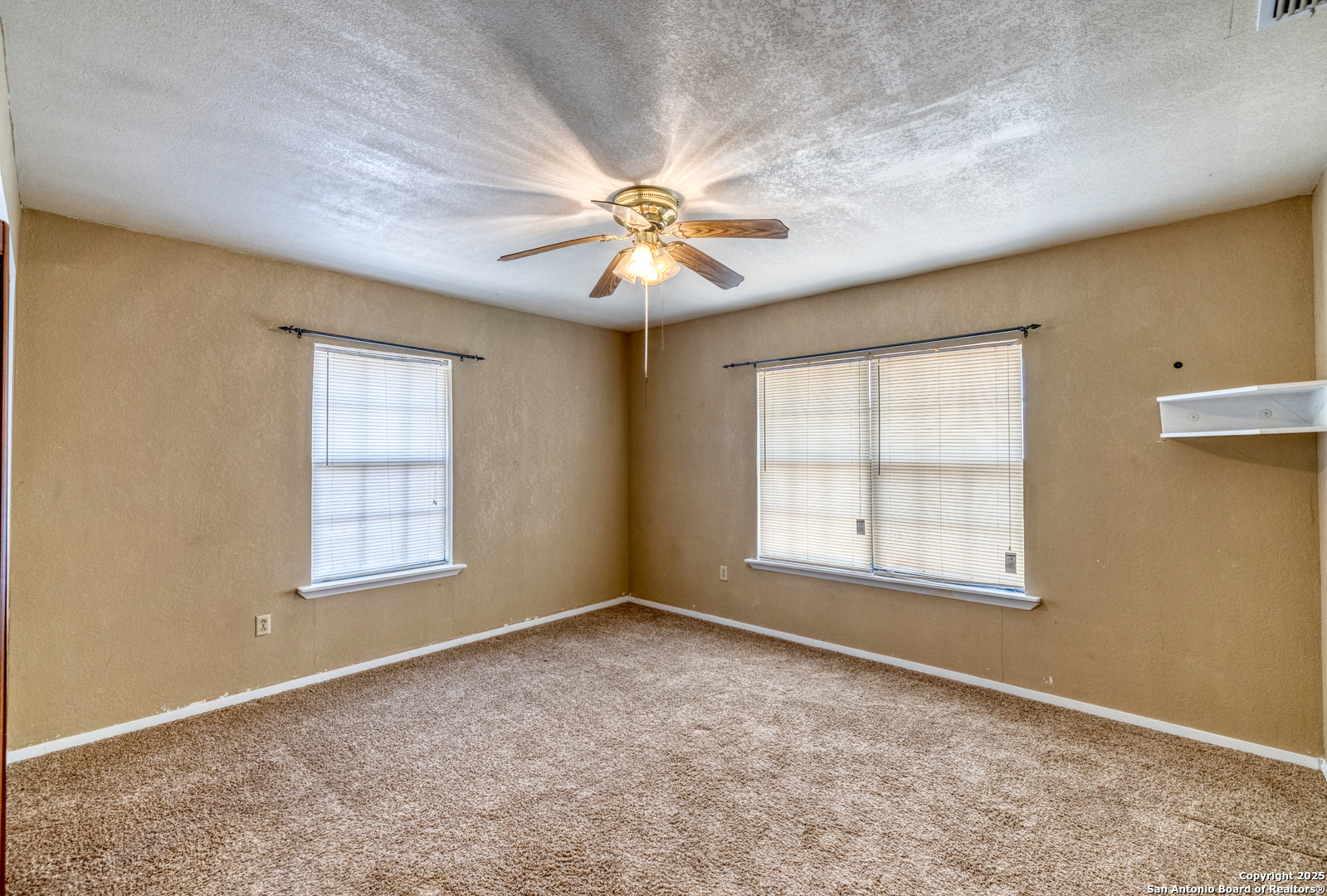 1390 Windmill Road Uvalde, TX 78801 - Photo 12 of 44 an empty room with chandelier fan and windows