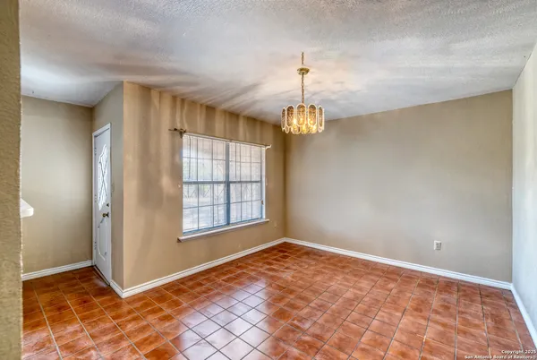 a view of an empty room with window and chandelier fan