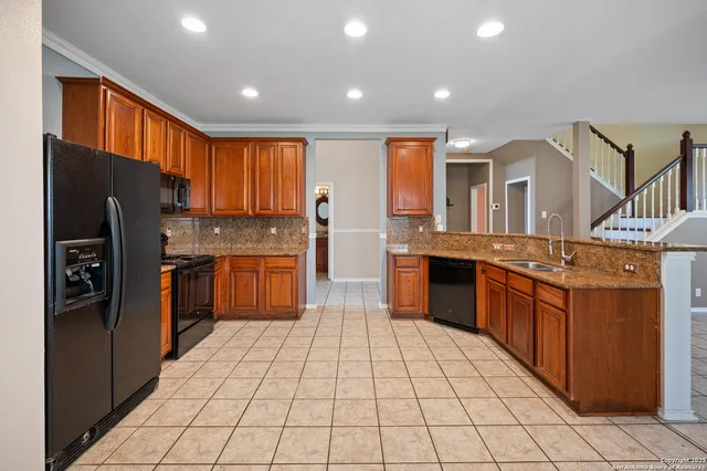 a kitchen with stainless steel appliances granite countertop a refrigerator a sink a stove a dining table and chairs