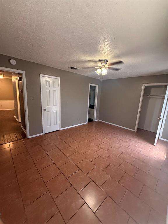 708 East Pecan Street, Unit 712 Hurst, TX 76053 - Photo 12 of 15 Spacious Master bedroom with closet featuring terra cotta-style tile flooring, light neutral wall paint, and a ceiling fan with integrated lighting