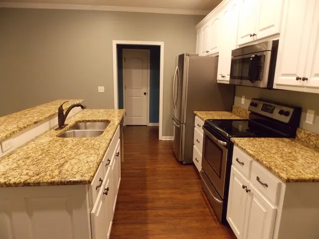 a kitchen with granite countertop counter space a sink a refrigerator and a stove