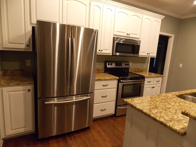 a kitchen with granite countertop a refrigerator stove and microwave