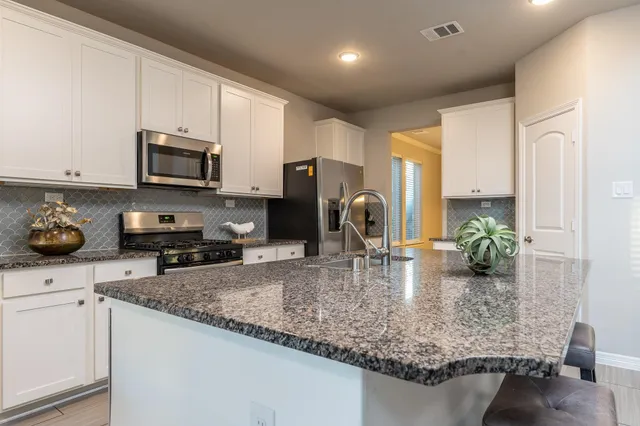 a kitchen with kitchen island granite countertop a sink a stove and cabinets