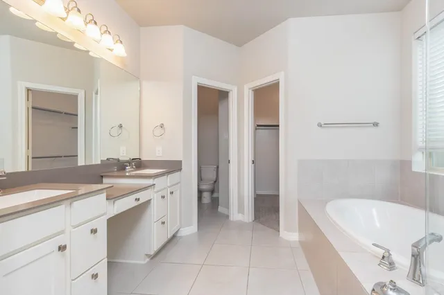 a spacious bathroom with a granite countertop sink a bathtub and a mirror