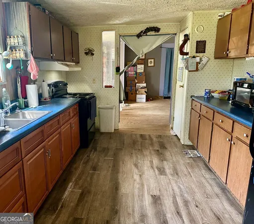 a kitchen with granite countertop wooden floors stainless steel appliances a sink and cabinets