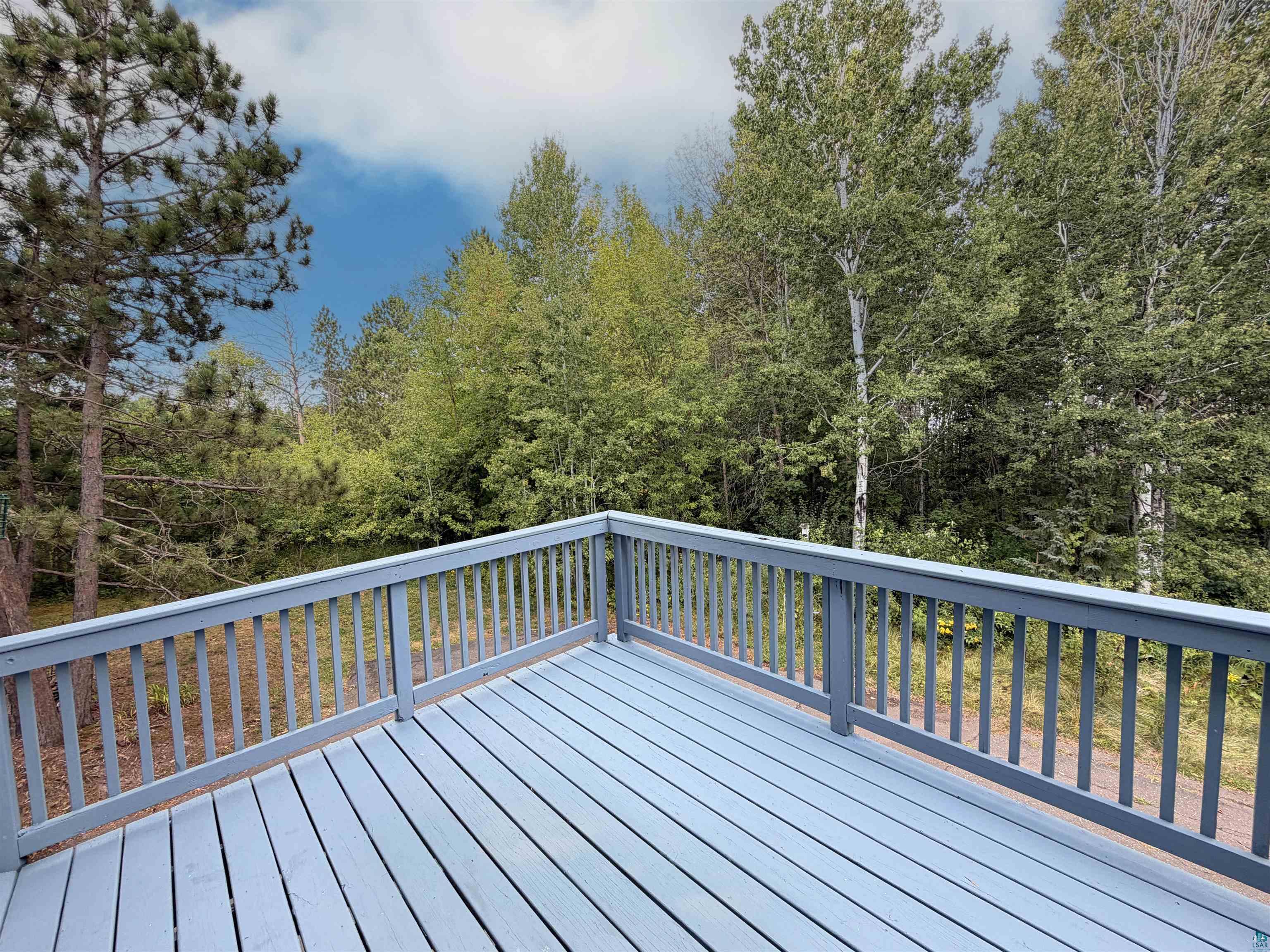 109 Prentice Heights Road, Unit 2 Ashland, WI 54806 - Photo 8 of 23 Expansive outdoor deck with a painted wooden surface and a surrounding railing, framed by mature trees