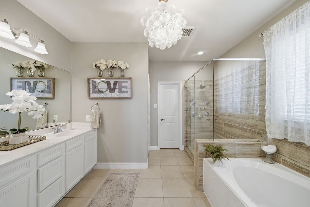 9614 Carson Lane Iowa Colony, TX 77583 - Photo 23 of 50 Elegant spa-like bathroom featuring a double-sink vanity, glass-enclosed shower, relaxing soaking tub with self-cleaning jets, and a stunning bubble chandelier that adds the perfect touch of luxury.