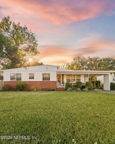 a view of a house with a big yard and large trees