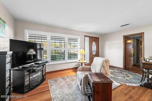 a view of an empty room with wooden floor and a window