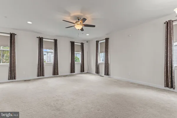 a view of a big room with windows and chandelier fan