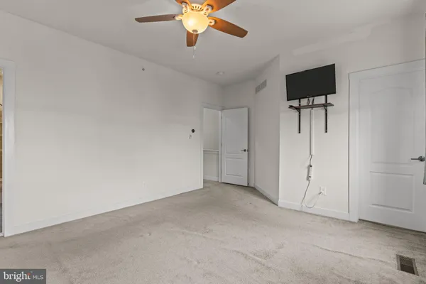 an empty room with closet and a chandelier fan