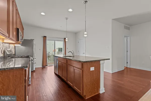 a kitchen with stainless steel appliances granite countertop wooden floors and sink